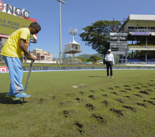 Clear skies but no cricket... Ground staff dig up the field to assist with drying under the supervision of umpire Gregory Brathwaite (C) during day 3 of the 4th and final Test between West Indies and India © AFP