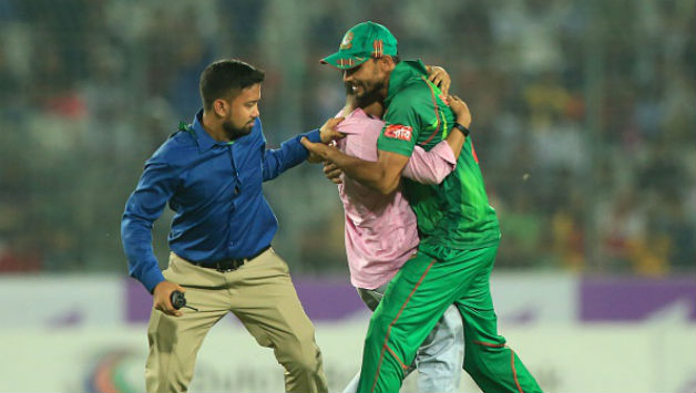 A Bangladesh security official (left) attempts to prevent a supporter who ran onto the field (centre) from embracing Mashrafe Mortaza (right) © AFP